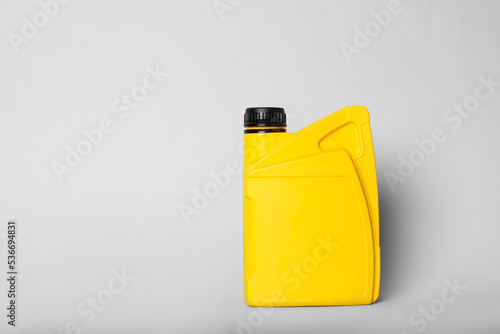 Motor oil in yellow canister on light background, space for text