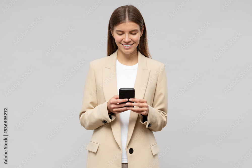 Woman CEO in jacket using phone to make appointment with partners, isolated on gray background Woman CEO in jacket using phone to make appointment with partners, isolated on gray background