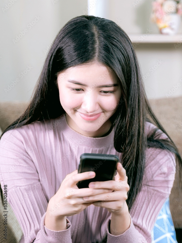Cheerful young pretty woman use smartphone in living room Cheerful young pretty woman use smartphone in living room