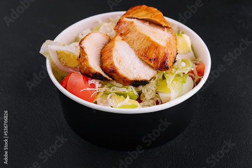 Delivery bowl with Caesar salad isolated on black background