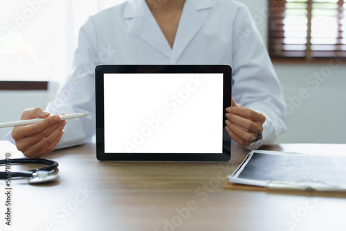 Slika na platnu Asian female doctor holds computer tablet to customer, white screen can insert t