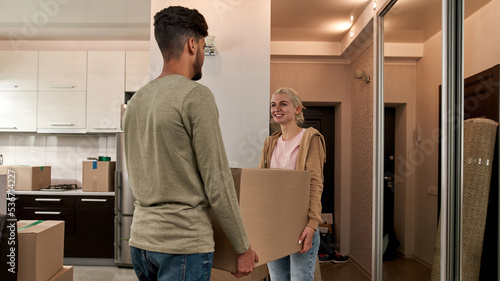 Couple carrying box with things in new apartment © Svitlana