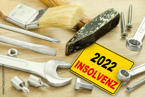 Deutsches gelbes Schild mit Insolvenz im Jahr 2022 und Werkzeug auf Holz