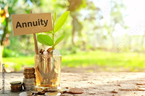 Investment on annuities concept. Coins in a jar with soil and growing plant in nature background.