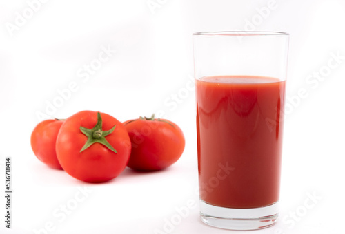 Tomato juice in a glass and ripe tomatoes on a white background