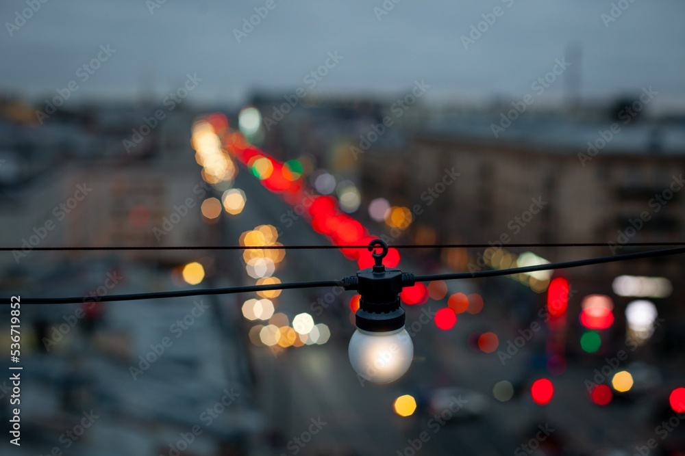 A white light bulb over the city's night avenue