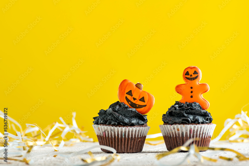 Funny Halloween cupcakes or muffins decorated with gingerbread on yellow background. Funny Halloween cupcakes or muffins decorated with gingerbread on yellow background.