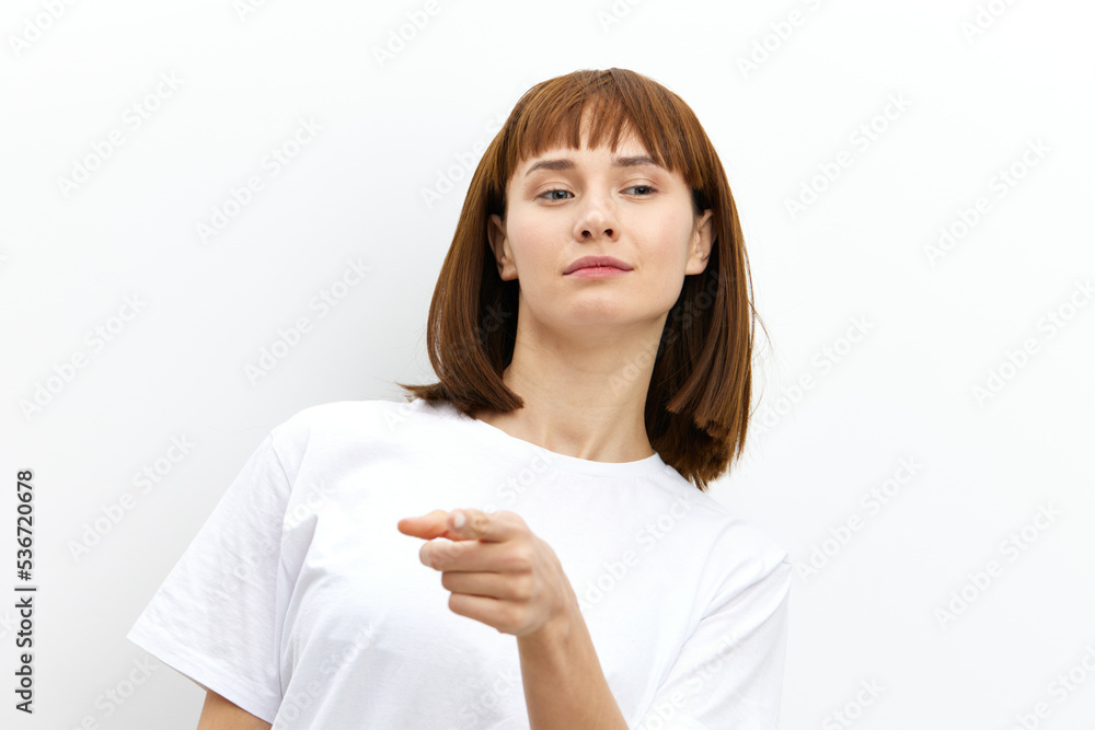 a funny, emotional, beautiful woman smiles broadly and gestures with her fingers towards at camera. standing on the background for inserting an advertising layout a funny, emotional, beautiful woman smiles broadly and gestures with her fingers towards at camera. standing on the background for inserting an advertising layout