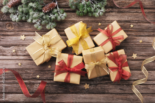 Heap of Christmas gift or present boxes with holiday decorations and snowy fir tree on wooden table top view.