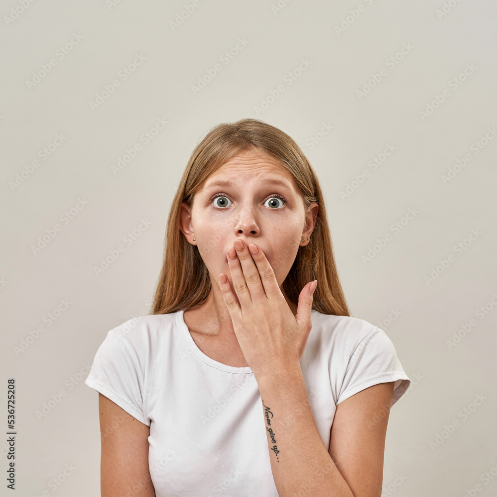 Frightened or shocked teenage girl covering mouth Frightened or shocked teenage girl covering mouth