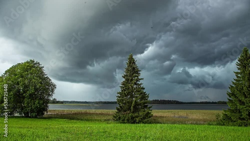 Time lapse of dense storm clouds moving together over a lake in the countryside. photo