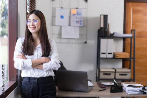 Business concept, Confident businesswoman is standing with arms crossed and looking outside window