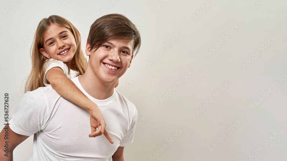 Teenage boy holding blonde little sister piggyback Stock Photo Adobe