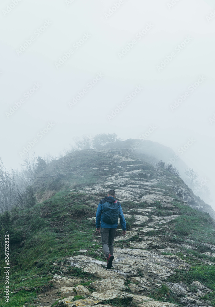 Alone man with equipment in the nature with several fog hiking the mountain