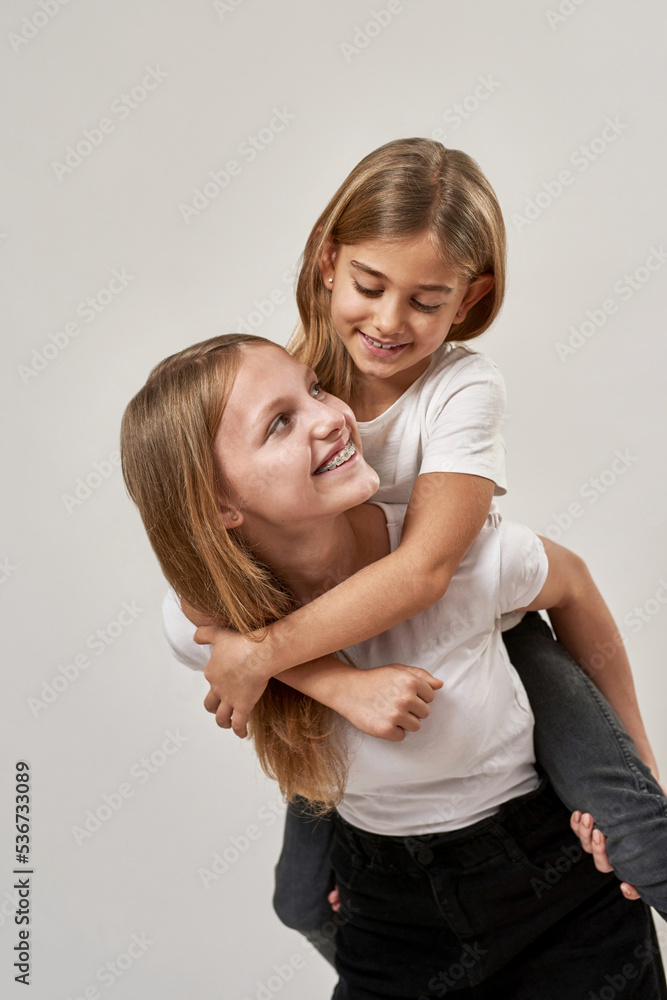 Teenage girl hold little sister piggyback on white Teenage girl hold little sister piggyback on white