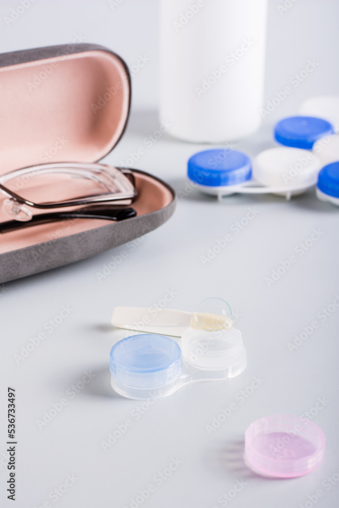 Contact lens on an open storage container on the background of a case with glasses. Vertical view Contact lens on an open storage container on the background of a case with glasses. Vertical view