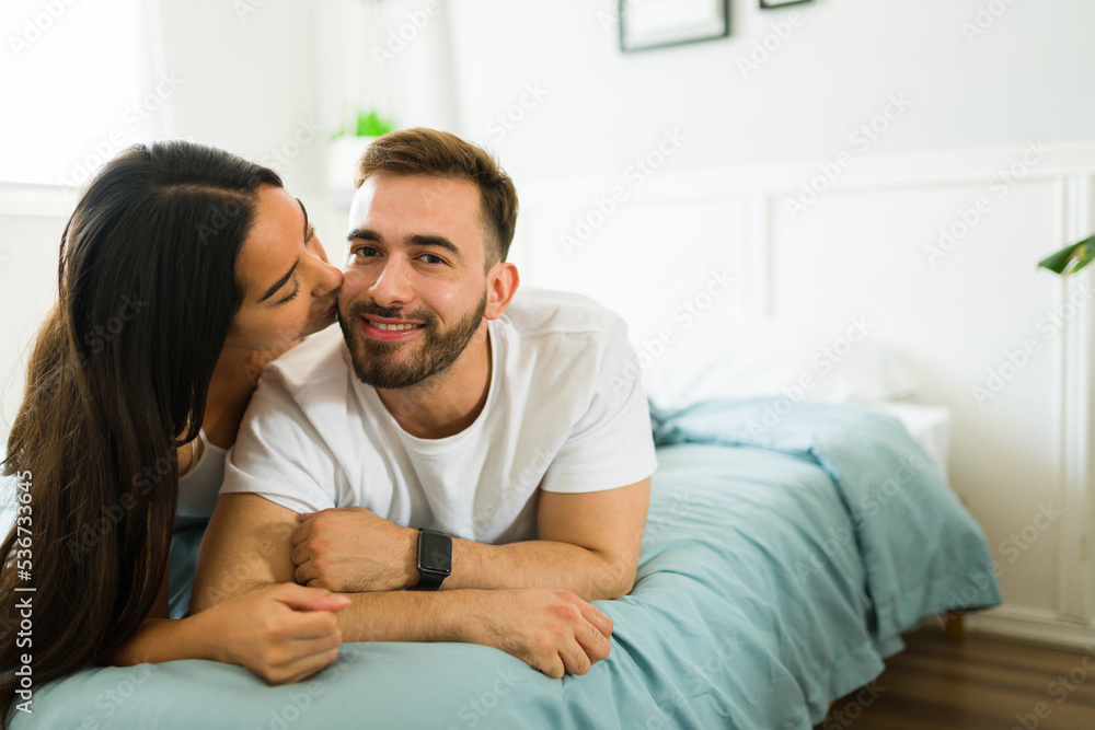 Couple in pajamas kissing and smiling while in the bedroom Couple in pajamas kissing and smiling while in the bedroom