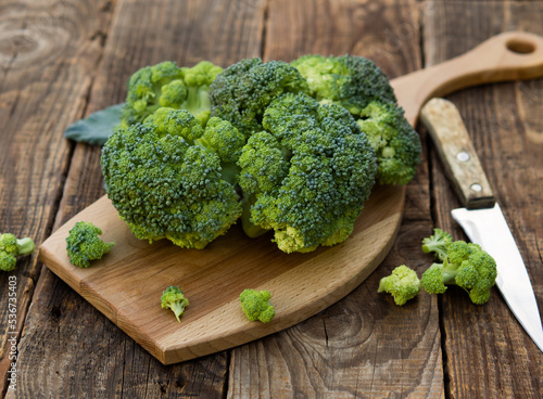 fresh green broccoli on a wooden cutting board with a knife. Broccoli cabbage leaves.
