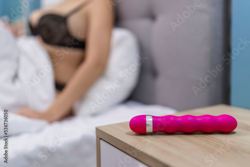 Young woman holding sex toy dildo vibrator in bed