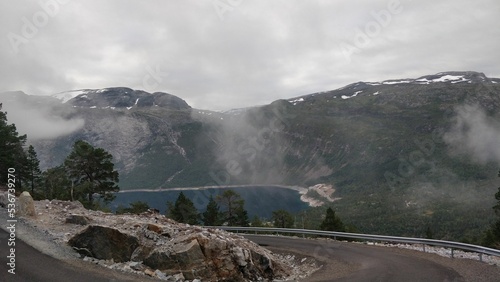 Rocky mountain with a small lake covered with clouds photo