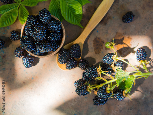 fresh blackberries in a wooden bowl and spoon on an old table photo