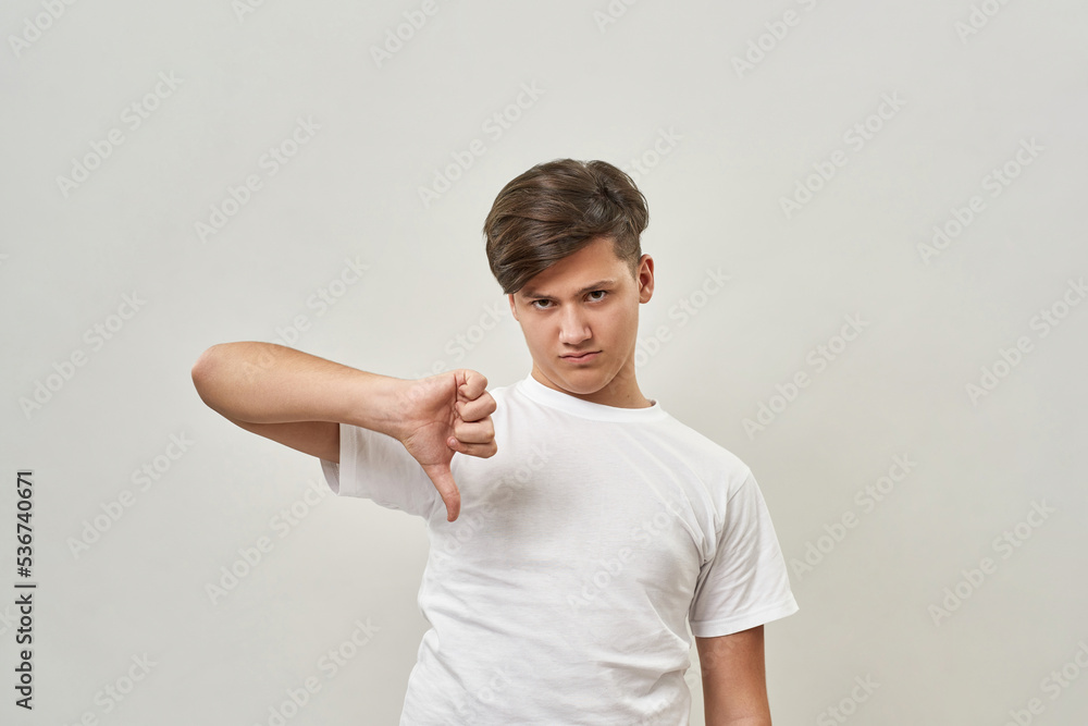 Dissatisfied european teenage boy show thumb down Dissatisfied european teenage boy show thumb down