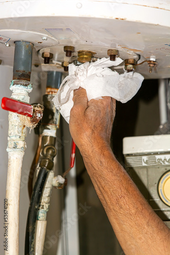 Solar boiler electrician. Solar water heater installer. Drains the boiler from the leak. with paper
