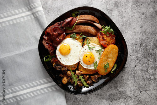 Close up shot of a big breakfast composed of eggs, potatoes, tomato and meat