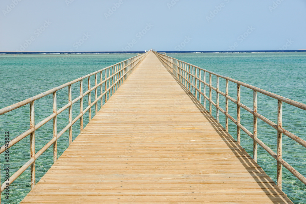 Very long wooden pier footbridge in ocean sea. High quality photo