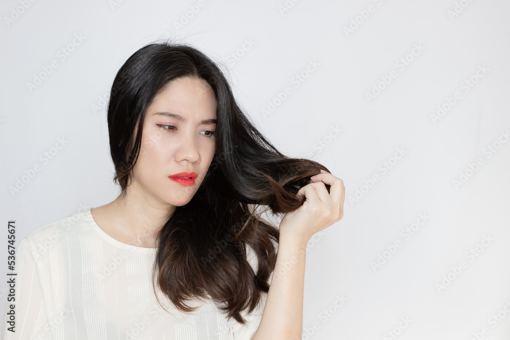 Asian beautiful woman holds and looking her tip hair to see split and dry hair with worry face Asian beautiful woman holds and looking her tip hair to see split and dry hair with worry face