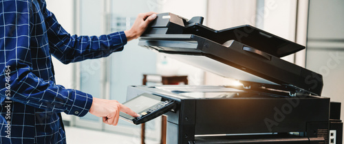Copier printer, Close up hand office man press copy button on panel to using the copier or photocopier machine for scanning document printing a sheet paper. photo