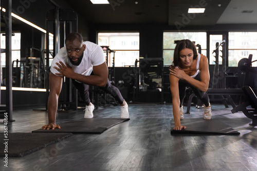 Portrait of beautiful young sports couple on a plank position.