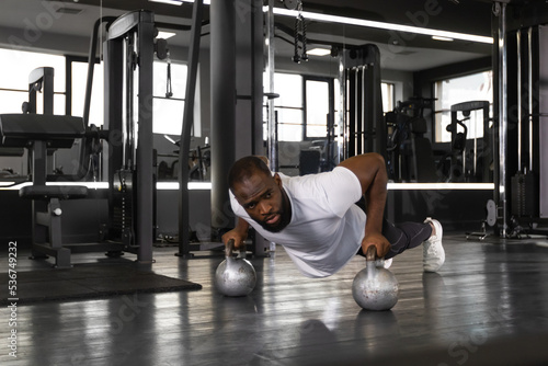 Sporty african man doing push-up in a gym. © ty