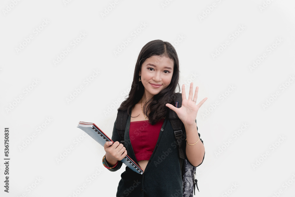 A fifth year college student holds up five fingers as she poses for a studio photo isolated on a plain white background. Stop hand gesture. Waving hello. A fifth year college student holds up five fingers as she poses for a studio photo isolated on a plain white background. Stop hand gesture. Waving hello.