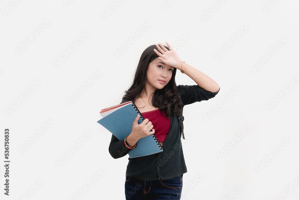 A female college student who is unwell due to academic-related stress feels the temperature on her forehead. Studio shot isolated on a white background. A female college student who is unwell due to academic-related stress feels the temperature on her forehead. Studio shot isolated on a white background.