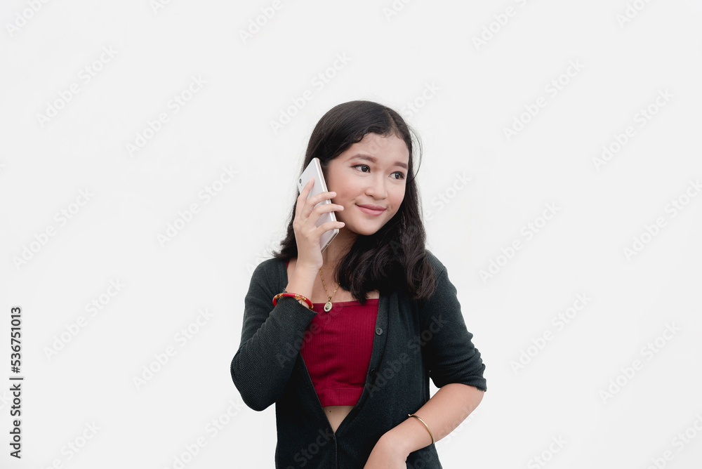 A smiling young lady is on the phone with her friend as she gossips about the trending issue. Studio shot isolated on a white background. A smiling young lady is on the phone with her friend as she gossips about the trending issue. Studio shot isolated on a white background.