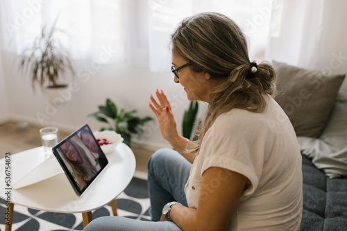 Adult woman having video call at home using tablet