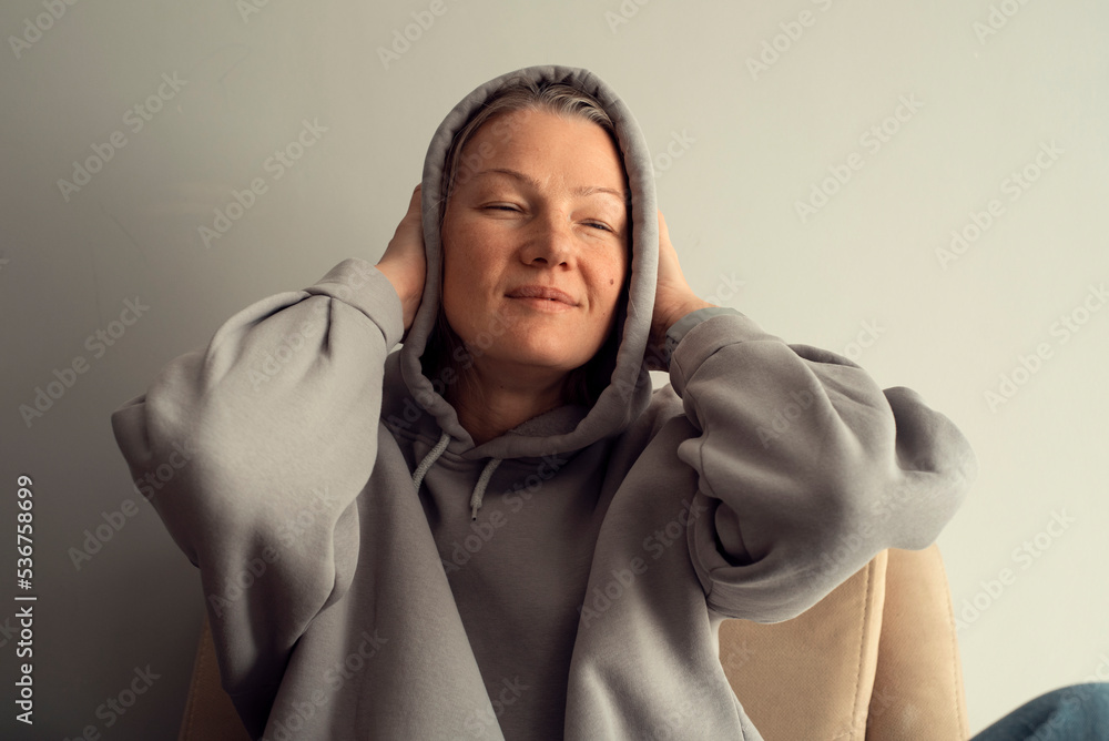 Young European woman in warm knitted clothes sitting on the chair at living room Young European woman in warm knitted clothes sitting on the chair at living room