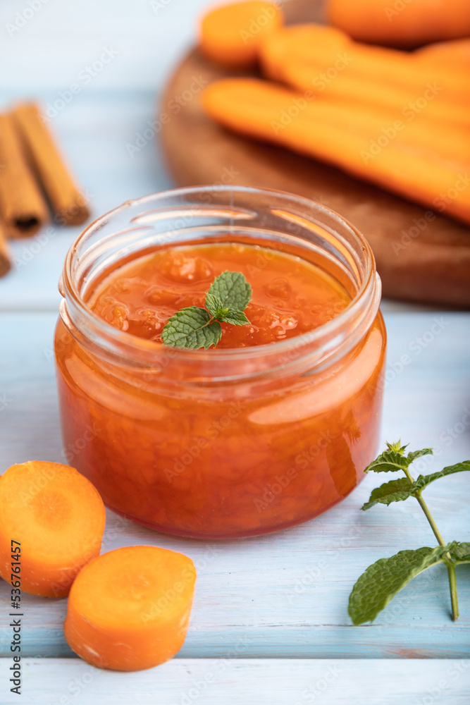 Carrot jam with cinnamon in glass jar on blue wooden. Side view, selective focus. Carrot jam with cinnamon in glass jar on blue wooden. Side view, selective focus.