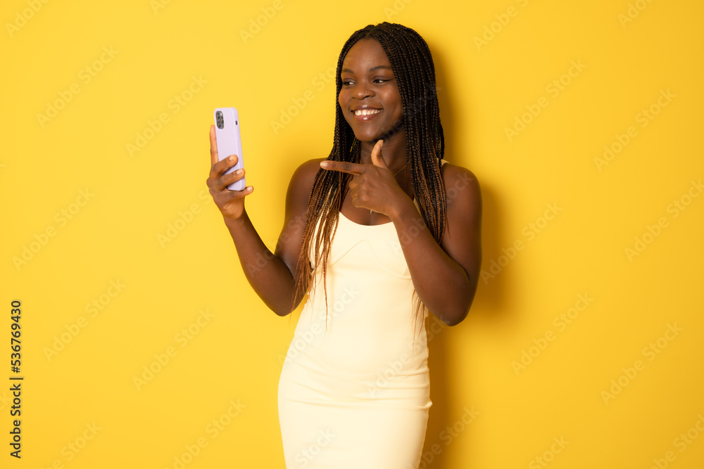 Young african american woman using smartphone standing over isolated yellow background very happy pointing with hand and finger Young african american woman using smartphone standing over isolated yellow background very happy pointing with hand and finger