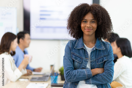Portrait of a charming African businesswoman in a business office meeting room while working with multi-ethnic colleagues.