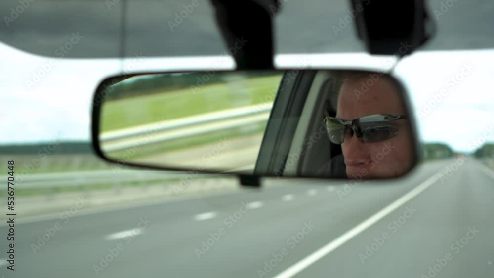 White man driving car on highway reflected in rear view mirror in Russia White man driving car on highway reflected in rear view mirror in Russia