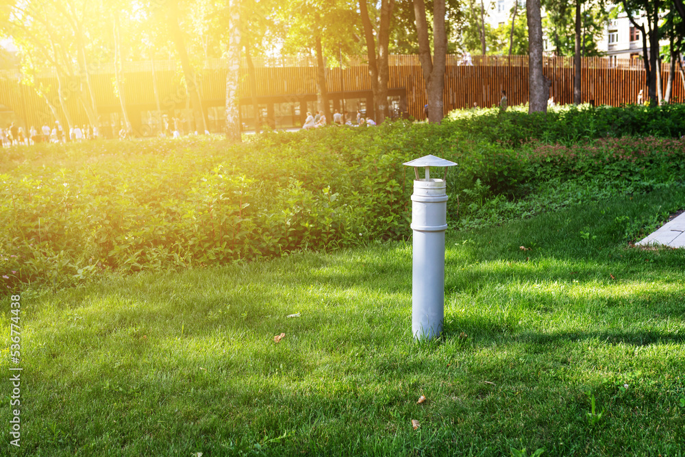 Park infrastructure. A ventilation pipe sticks out of a green lawn in a multi-level park Park infrastructure. A ventilation pipe sticks out of a green lawn in a multi-level park