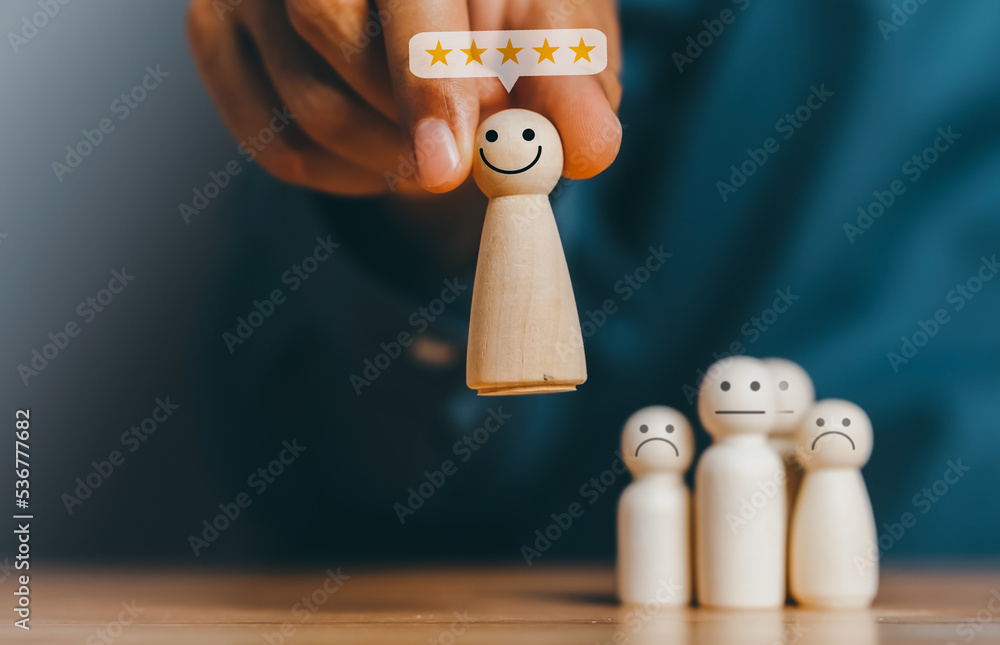 Fototapeta premium Quality assurance, Guarantee, Standards, ISO certification. excellent business services rating customer experience. Satisfaction survey. Hand of a businessman chooses a smiley face on wood block.