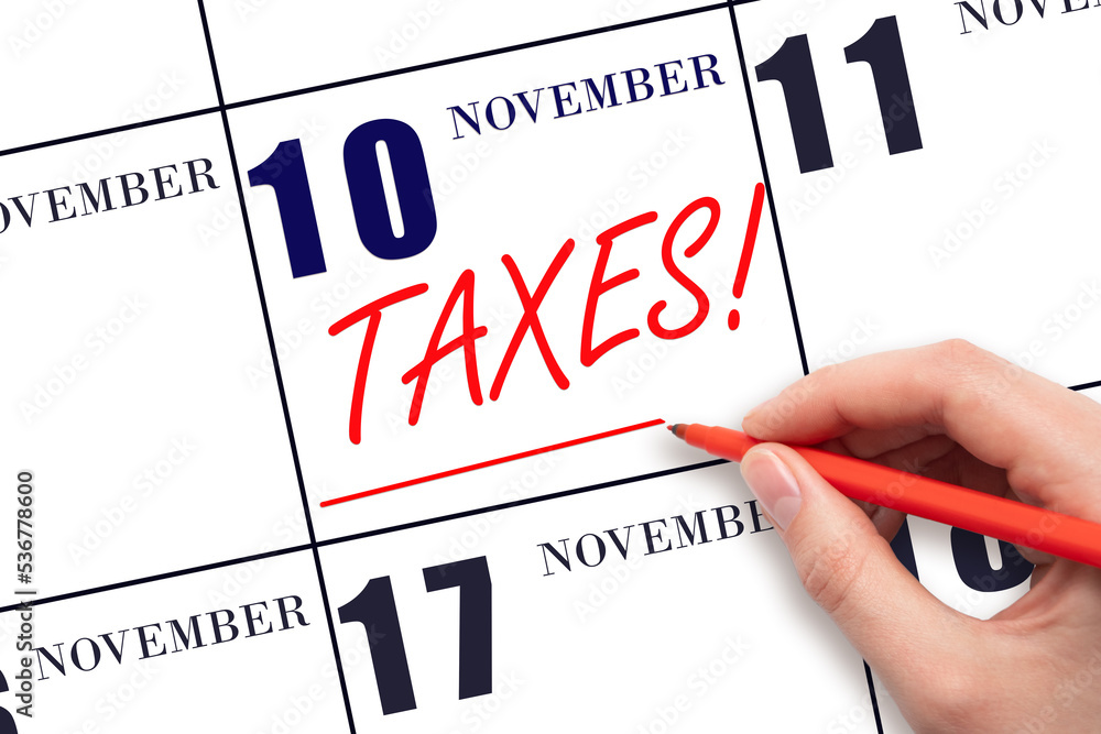 Hand drawing red line and writing the text Taxes on calendar date November 10. Remind date of tax payment Hand drawing red line and writing the text Taxes on calendar date November 10. Remind date of tax payment