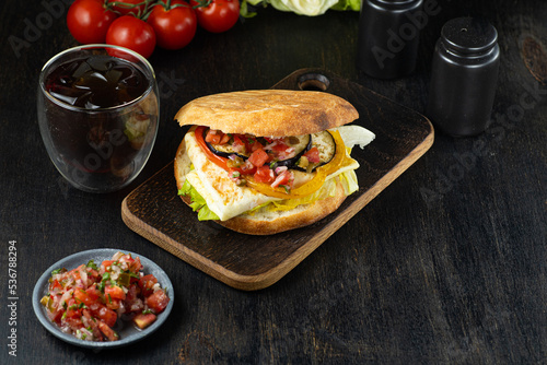 Israeli fast food sabich sandwich with vegetables, eggs on wooden background. vertical