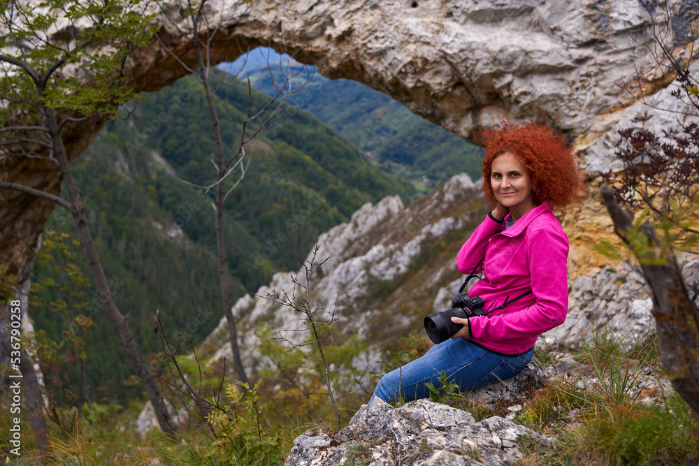 Woman tourist with camera by a natural rock portal