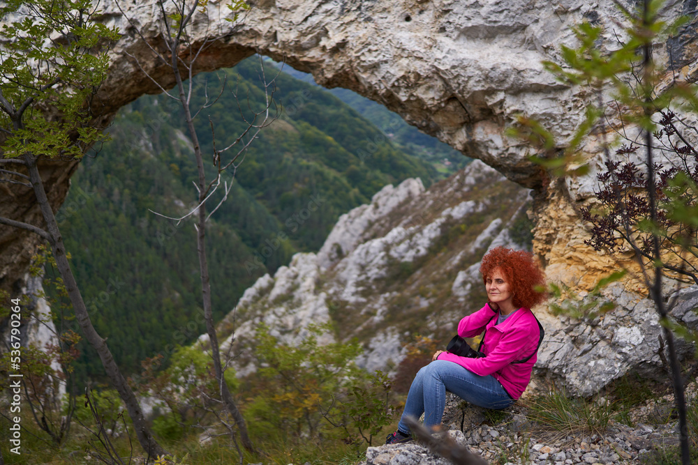 Woman tourist with camera by a natural rock portal Woman tourist with camera by a natural rock portal