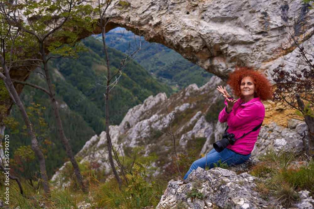 Woman tourist with camera by a natural rock portal