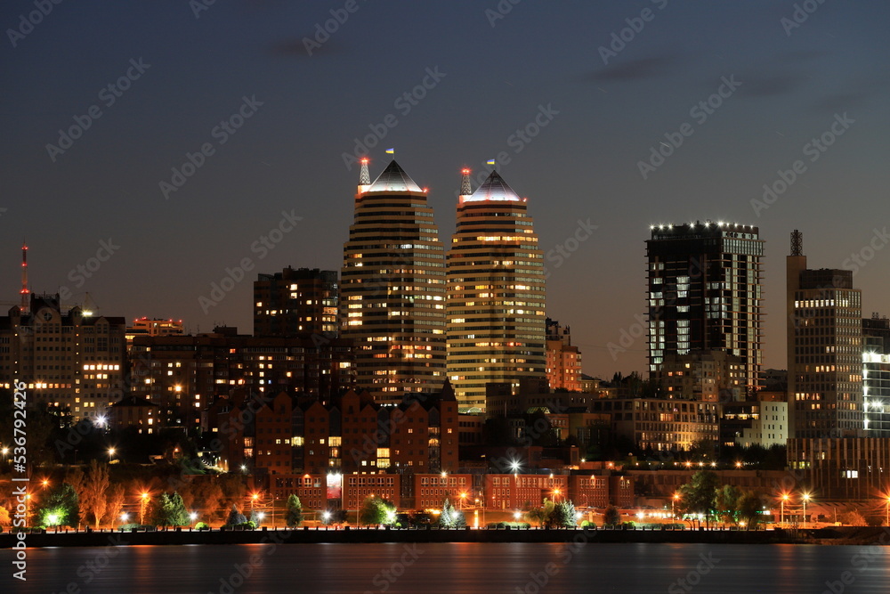 Obraz premium Big city at night. Beautiful modern buildings, skyscrapers and towers are reflected in Dnipro river evening, Ukraine. Dnepr.